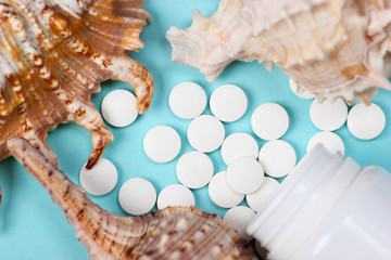 Obraz na płótnie Canvas Mineral tablets (calcium) with seashells on a blue background