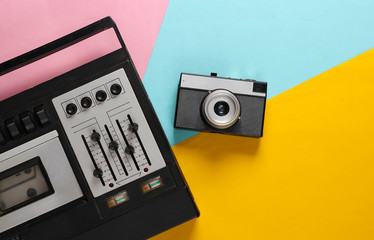 Retro audio tape recorder and film camera. Retro media on colored background. Top view. 80s