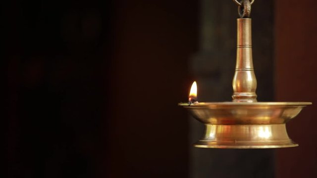 Traditional Indian brass oil lamp burning with glowing flame in darkness