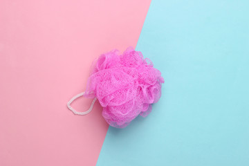 Pink bath sponge on a blue-pink pastel background. Top view. Minimalism