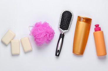 Fototapeta na wymiar Bath, beauty products on white background. Shampoo bottle, sponge, soap and hair brush. Top view. Flat lay