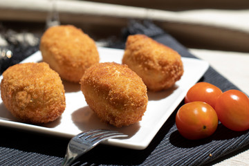 Croquettes with cherry tomatoes presented on white plate. horizontal view.