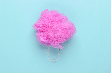 Pink bath sponge on a blue pastel background. Top view. Minimalism