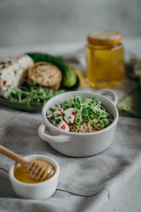 salad with quinoa, microgreens, cucumber, cottage cheese searved on gray background with  honey, linen napkin. clean eating for immunity