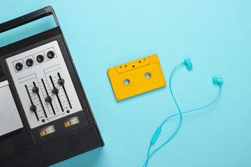 Fototapeta premium Retro audio tape recorder, earphones and audio cassette. Retro media on blue background. Top view. 80s