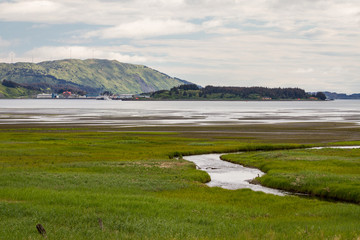 Mountain with blue sky tall grass and a river stream Kodiak, Alaska
