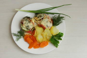 baked zucchini with vegetables on a white plate, for proper nutrition, with a side dish of potatoes and carrots