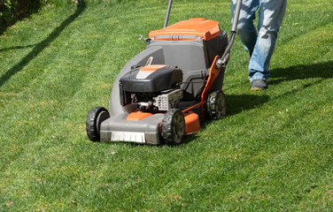 Man moves with lawnmower mows green grass