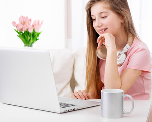 Young attractive girl is sitting in front of an open laptop at working space