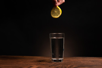 lemon in glass of water on black background