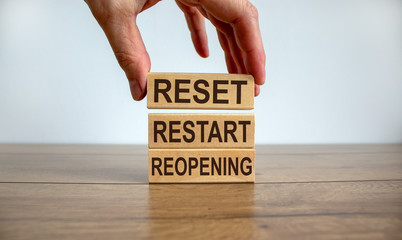 Male hand placing a block with word 'reset' on top of a blocks tower on wooden table. Beautiful...