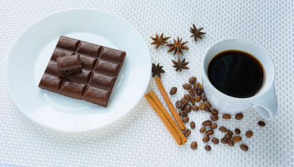 aromatic cup of coffee with porous chocolate among coffee beans, star anise and cinnamon sticks on a white background