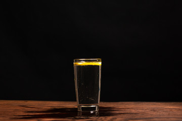 lemon in glass of water on black background