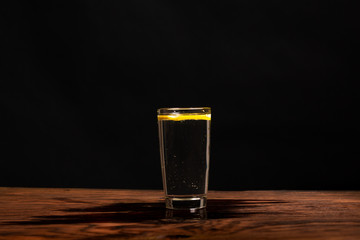 lemon in glass of water on black background