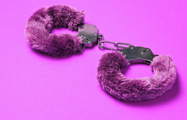 Handcuffs for sex games on pink background. Sexual bdsm toy. Fetish, erotic concept.