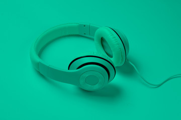 Classic white wired headphones in green neon light. Retro style. 80s. Pop culture. Top view. Minimal Music Concept