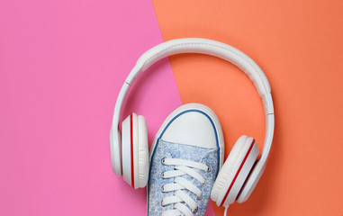 White Sneakers with headphones on colored background. Music concept. Flat lay, minimal.