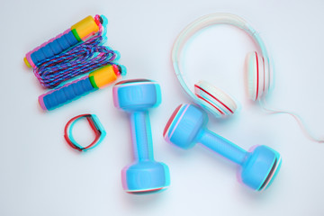 Dumbbells, smart bracelet, headphones,  jump rope on a white background. Minimalistic sport concept. Glitch effect. Top view.