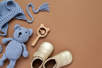Flat lay composition with baby accessories set: crib shoes, teddy bear toy, knitted hat, wooden...