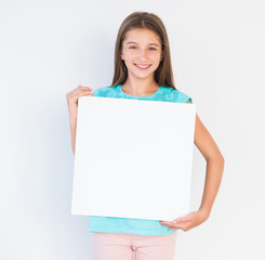 Adorable teen girl holding blank white canvas for copy space