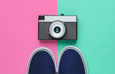 Hipster style flat lay. Classic sneakers and retro film camera on a pastel colored background. Top...
