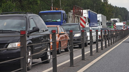 Naklejka premium Traffic jam - a many cars on the road with cable fence on a summer day at rush hour, loss of time