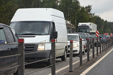 Traffic jam on oncoming lane - a lot of cars on the suborban highway with cable fence on a summer...