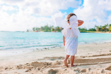 Naklejka na ściany i meble Beautiful young girl wearing angel wings on the beach