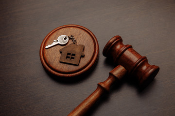 Judge gavel and key chain in shape of two splitted part of house on wooden background. Concept of...