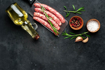 
raw sausages with ingredients over a meat knife on a stone background with copy space for your text