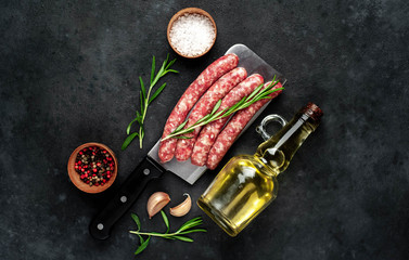 Obraz na płótnie Canvas raw sausages with ingredients over a meat knife on a stone background with copy space for your text