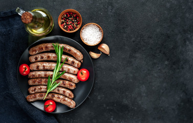 Obraz na płótnie Canvas grilled sausages with ingredients on a plate on a stone background with copy space for your text