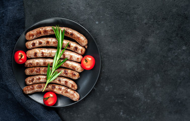 
grilled sausages with ingredients on a plate on a stone background with copy space for your text