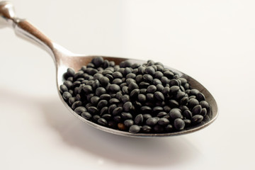 Close-up on black beluga lentils on a spoon. Isolated on white background.