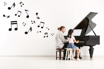 Music teacher giving piano lessons to little girl