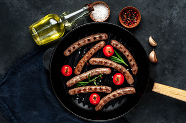 grilled sausages with tomatoes and
rosemary in
pan on stone background