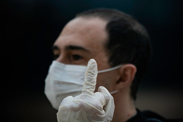 A man wearing a mask and gloves showing the middle finger during the 2020 COVID-19 corona virus outbreak