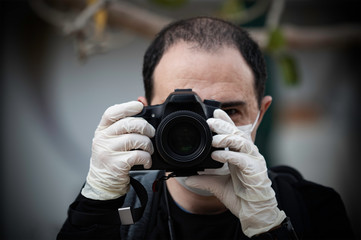 A photographer looking through the camera while wearing a mask and gloves during the 2020 COVID-19 corona virus outbreak