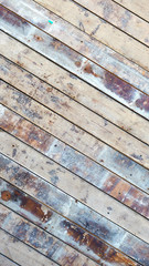 Dirty surface from old unpainted floorboards with stains of rust, oil and lime. Plank stacked at an angle diagonally across the frame. Background or wallpaper for phone or mobile. View from above