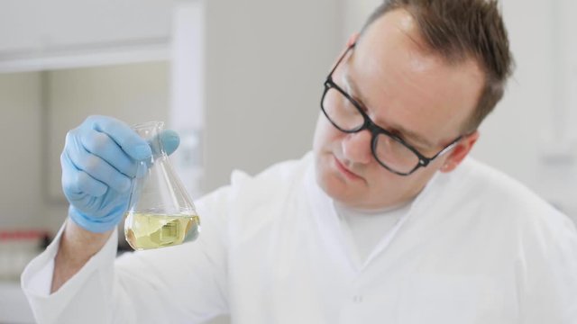 Close up of chemist working with hemp CBD oil and tablet in laboratory