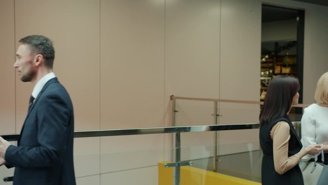 Slow motion of businesspeople men and women talking in office building lobby standing in groups discussing work. People and conversation concept.