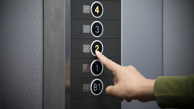 エレベーターのボタンを押す指
