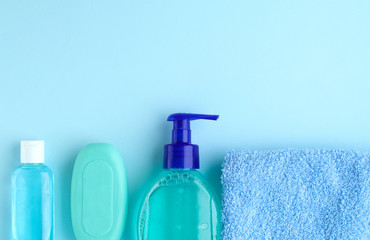 Personal care products on a blue background.Hand sanitizing gel, antibacterial liquid and solid lump soap and a blue Terry towel on a blue background.Space for text.Selective focus.Copy space.