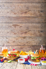 Celebrating Independence Day, July 4. Traditional American Memorial Day Patriotic Picnic with burgers,  french fries and snacks, Summer USA picnic and bbq concept, Old wooden background