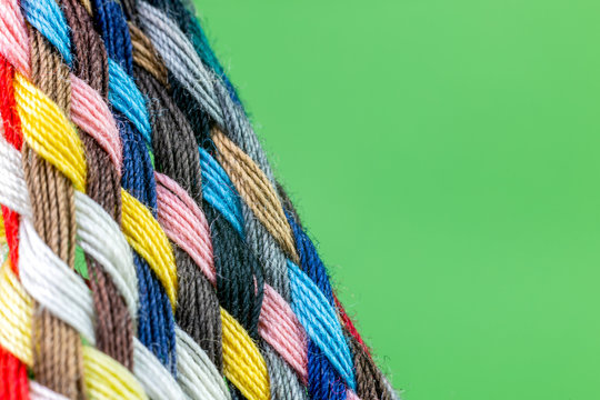strip of braided colored cotton threads with green background