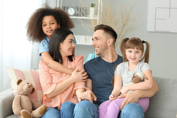 Happy couple with little adopted children at home