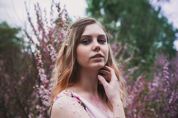 Girl in a delicate dress with mehendi on the body, in flowering almonds