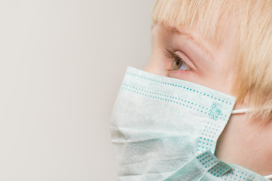 Close up of child face in surgical mask, white background. Prevention of bacterial infection Covid 19