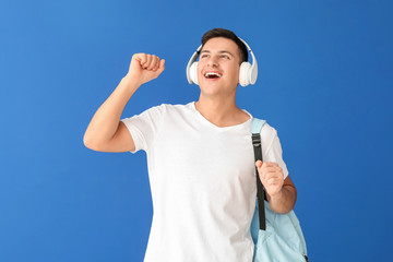 Portrait of male student listening to music on color background
