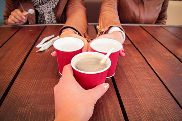 Closeup of hands with coffee cups in a cafe